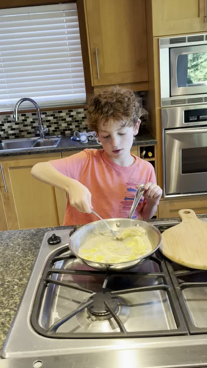 Ten-year-old cooking eggs on a real stove.